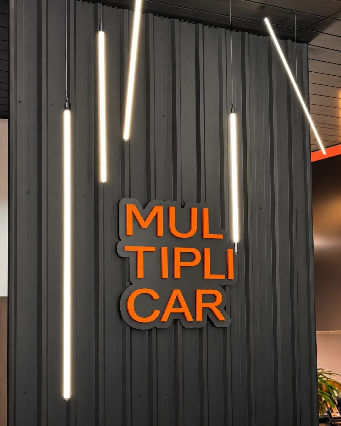 Letreiro MultipliCar laranja com luzes pendentes