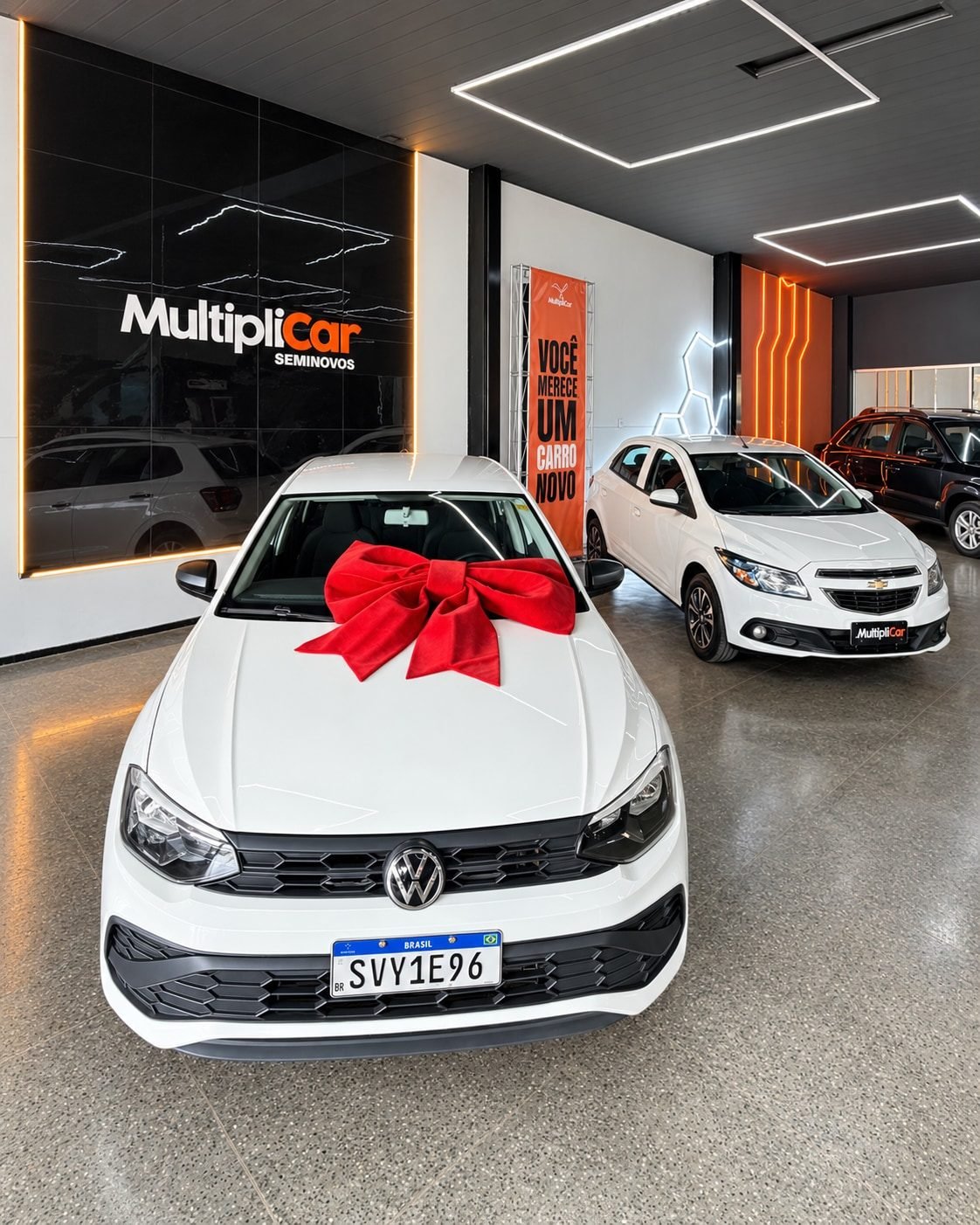 Carro branco com laço vermelho pronto para entrega no showroom da MultipliCar